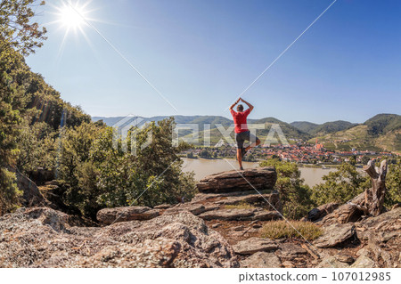 Panorama of Wachau valley (Unesco world heritage site) with man man practicing yoga against Weissenkirchen village in Austria Panorama of Wachau valley (Unesco world heritage site) with man man practicing yoga against Weissenkirchen village in Austria 107012985