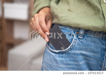 Lady hand takes out dark credit card with chip from jeans pocket to make online payment for ordered goods in store modern shopping and easy way to pay with money Lady hand takes out dark credit card with chip from jeans pocket to make online payment for ordered goods in store modern shopping and easy way to pay with money 107013017