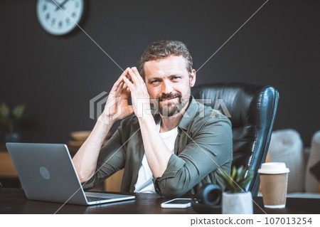 Confident businessman, exuding professionalism and leadership, makes pivotal decision based on meticulous computer analysis data. With hands folded in contemplative gesture, he gazes directly at 107013254