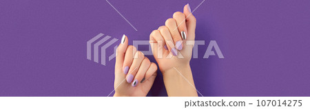 Beautiful groomed womans hands with matte lavender nail design on purple background. Manicure, pedicure beauty salon concept Beautiful groomed womans hands with matte lavender nail design on purple background. Manicure, pedicure beauty salon concept 107014275