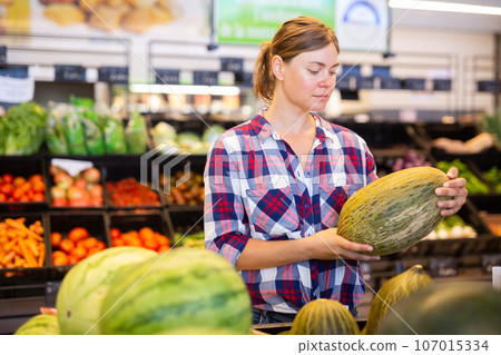 Young woman choosing ripe melon on counter at farmers market Young woman choosing ripe melon on counter at farmers market 107015334