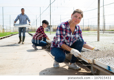 Smiling female agriculturist working in warm house Smiling female agriculturist working in warm house 107015431