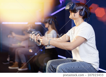 Man in virtual reality glasses controls superhero with joystick in exciting action game simulator Man in virtual reality glasses controls superhero with joystick in exciting action game simulator 107015433