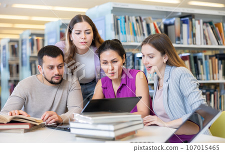 Group portrait of smiling positive engaged in research, working together in library 107015465