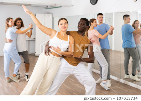 Woman and man practicing modern dance moves in pair during group class Woman and man practicing modern dance moves in pair during group class 107015734