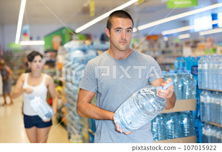 Man choosing still water in plastic bottle while shopping in supermarket Man choosing still water in plastic bottle while shopping in supermarket 107015922