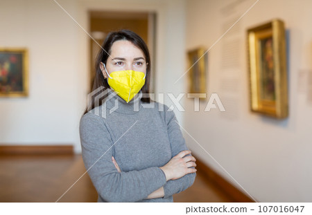 Woman in protective mask viewing collection of paintings in art museum Woman in protective mask viewing collection of paintings in art museum 107016047