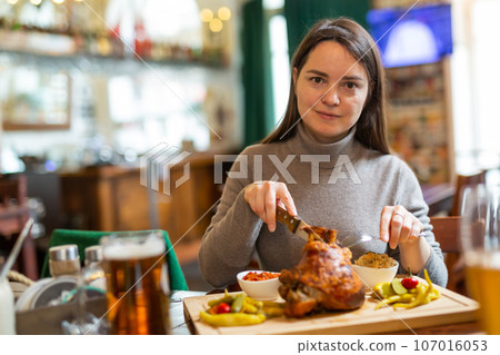 Female traveler tasting fried pork knuckle with beer in cafe 107016053