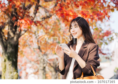 A woman going out during the autumn leaves season 107017165