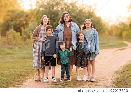 A large friendly family walks in a field in the summer 107017730