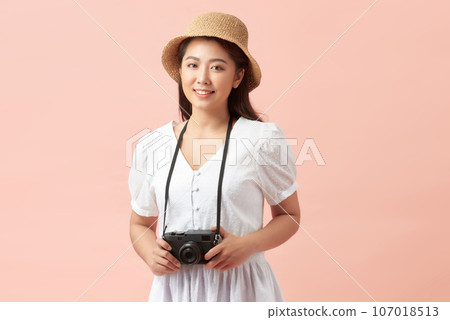 A young attractive Asian woman traveler in casual clothes wearing straw hat with backpack and camera 107018513