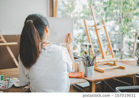 Art student drawing with watercolor painting on canvas doing some art projects on studio workshop Art student drawing with watercolor painting on canvas doing some art projects on studio workshop 107019031