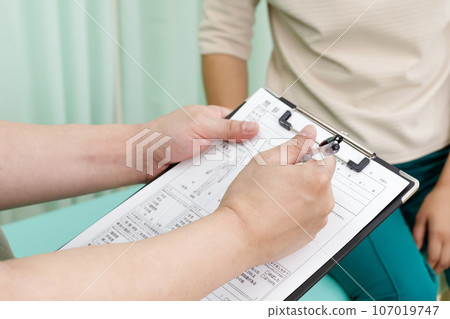 Interview. A male patient fills out the information and a female patient discusses her concerns. Interview. A male patient fills out the information and a female patient discusses her concerns. 107019747