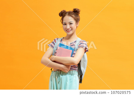 Photo portrait of cheerful student keeping book pile wearing spectacles isolated on yellow 107020575