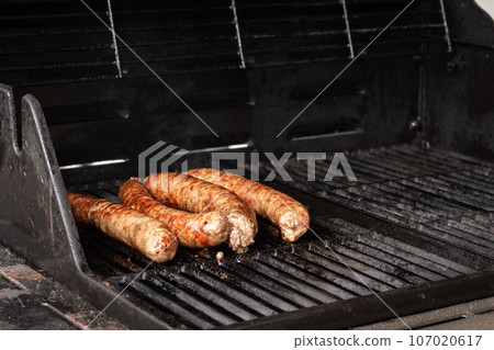 Sausages on the grill. Garden barbecue party. Pork sausages on the grill grate. Grilled bratwurst sausages. Picnic at backyard. Hot dog cooking. Unhealthy food. BBQ food concept. Sausages on the grill. Garden barbecue party. Pork sausages on the grill grate. Grilled bratwurst sausages. Picnic at backyard. Hot dog cooking. Unhealthy food. BBQ food concept. 107020617