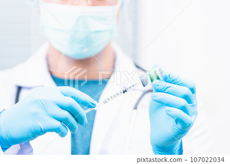 COVID-19 vaccine, Doctor man pull syringe on liquid bottle COVID-19 coronavirus vaccine for injection at hospital, nurse holding medicine and drug concept 107022034