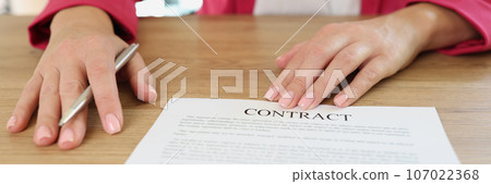Business woman offers to sign contract while sitting at table with pen in her hand. 107022368