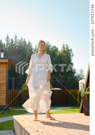 Barefoot woman dancing on terrace and waiving her dress Barefoot woman dancing on terrace and waiving her dress 107023146
