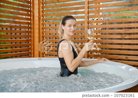 Beautiful woman with a glass of wine in hot tub - Stock Photo [107023161] -  PIXTA