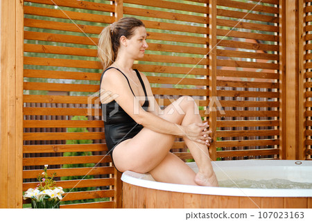 Woman sitting cross-legged on the edge of a jacuzzi Woman sitting cross-legged on the edge of a jacuzzi 107023163