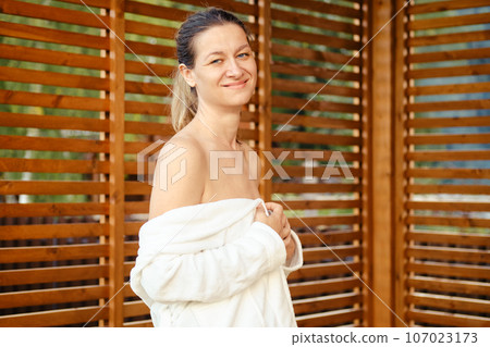 Portrait of an elegant, smiling woman wearing a bathrobe 107023173