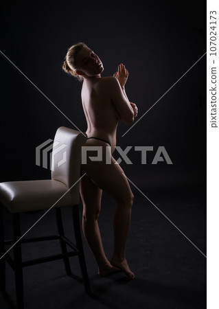 Seductive plump blonde woman naked on dark background with colour lights 107024173