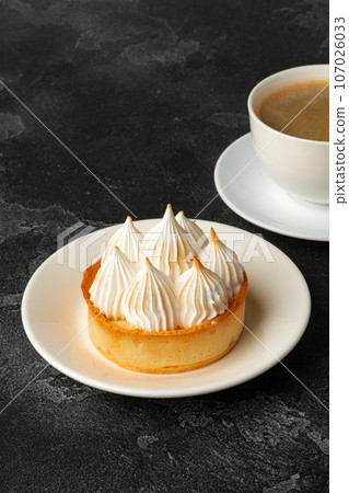 Meringue tart with coffee cup on dark gray background Meringue tart with coffee cup on dark gray background 107026033