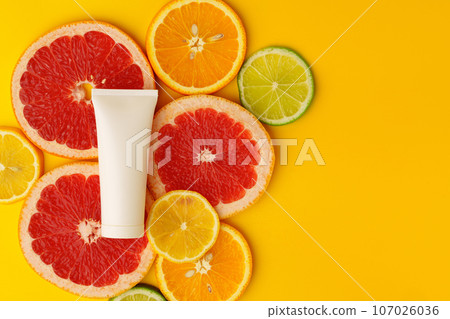 Cosmetic container on yellow background with cut citrus fruit flat lay Cosmetic container on yellow background with cut citrus fruit flat lay 107026036