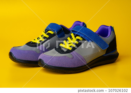Violet-blue female sneakers on yellow studio background Violet-blue female sneakers on yellow studio background 107026102