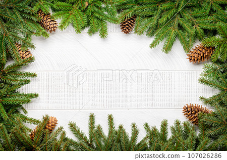 Christmas fir tree branch frame over white wood Christmas fir tree branch frame over white wood 107026286
