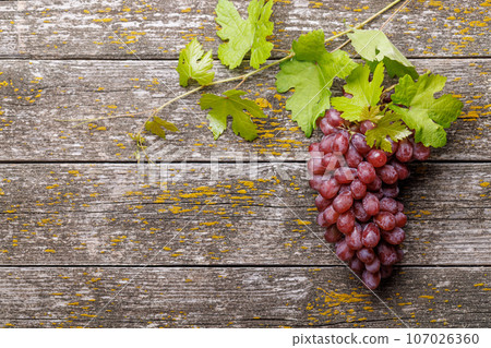 Grape with vine leaves on wooden table 107026360