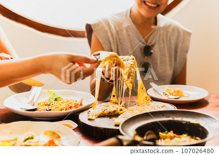 Woman hands taking slices of pizza with friends. Woman hands taking slices of pizza with friends. 107026480