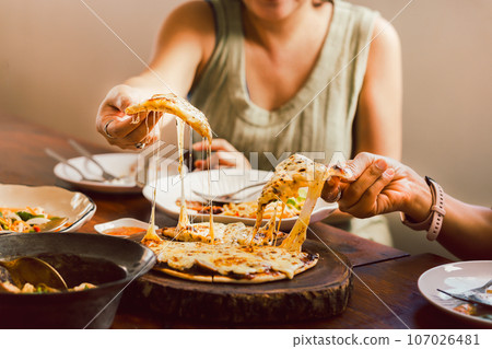 Woman hands taking slices of pizza with friends. Woman hands taking slices of pizza with friends. 107026481
