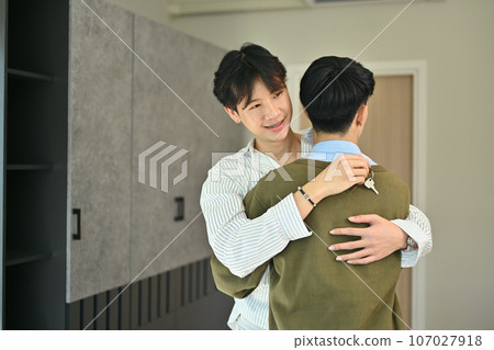 Married asian gay couple holding keys and hugging each other in new house. Loan, house ownership and relocation 107027918