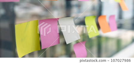 Blank colorful adhesive notes on glass wall of meeting room in creative office. Brainstorming, planning, developing and strategy 107027986