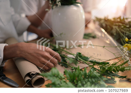 Young woman arranging flowers on wooden table. Leisure activity and lifestyle concept 107027989