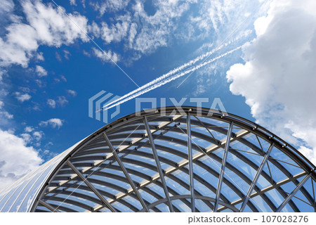 Airliner with Contrails Flying Above a Modern Airport 107028276