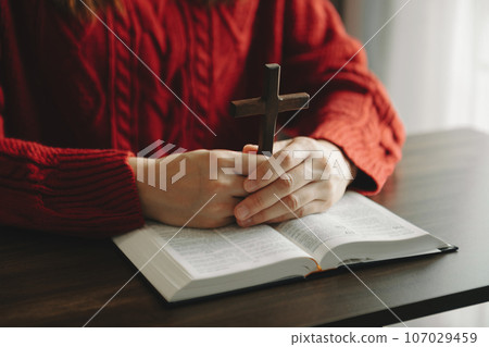 Woman sitting and studying the scriptures.The wooden cross in the hands. Christian education concepts The Holy Scriptures open Woman sitting and studying the scriptures.The wooden cross in the hands. Christian education concepts The Holy Scriptures open 107029459