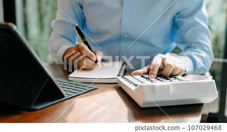 .Close up of businesswoman or accountant hand typing laptop working to calculate on desk about cost at home office. .Close up of businesswoman or accountant hand typing laptop working to calculate on desk about cost at home office. 107029468