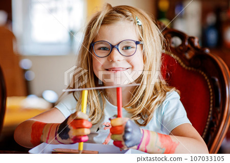 Little preschool girl painting with felt pens on hands. Creative cute child showing hands and arms painted with colorful pens or water colors. Laughing happy kid. 107033105