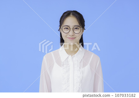 藍色背景下戴眼鏡的年輕女子的肖像 107033182