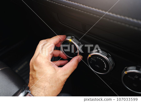 The driver hand adjusts the temperature of the car air conditioner in the car. The driver hand adjusts the temperature of the car air conditioner in the car. 107033599