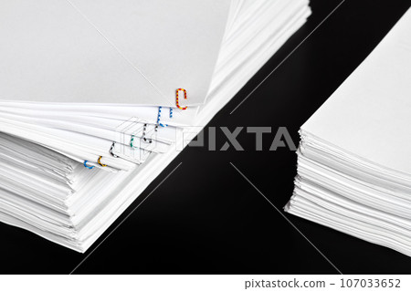 Stacks of papers with multicolored paper clips on a dark background 107033652