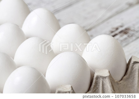 Close-up of Cardboard tray with white chicken eggs on wooden background 107033658