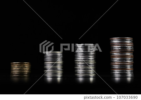 Stacks of metallic coins on a dark background Stacks of metallic coins on a dark background 107033690