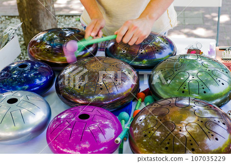 the musician plays colored hang drums, close-up the musician plays colored hang drums, close-up 107035229