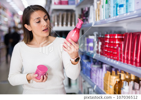 Happy girl choosing hair care treatments in cosmetics store 107036512