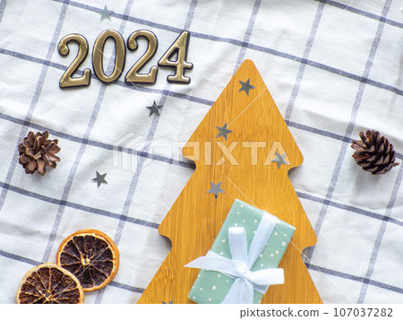 Empty christmas tree shaped wooden plate with 2024 on towel background Empty christmas tree shaped wooden plate with 2024 on towel background 107037282
