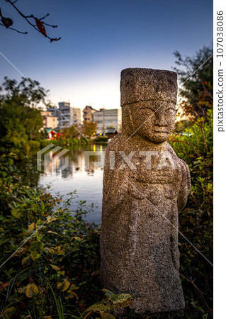 Autumn at Shinsen-en, the autumn-colored townscape reflected in Hojoju Pond, and a stone statue standing on the bank 107038086