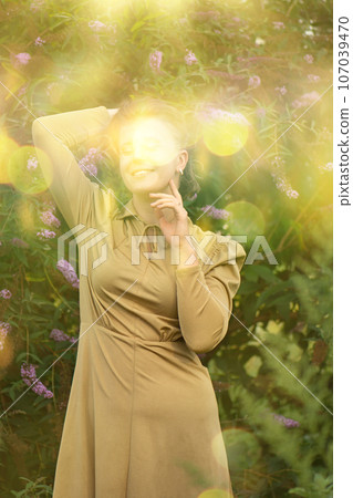 Girl in a simple dress in a buddleia flower field or butterfly bush. Girl in a simple dress in a buddleia flower field or butterfly bush. 107039470